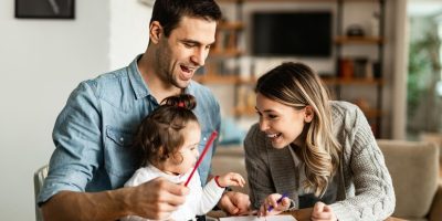 felices-padres-su-pequena-hija-divirtiendose-mientras-colorean-papel_637285-10221