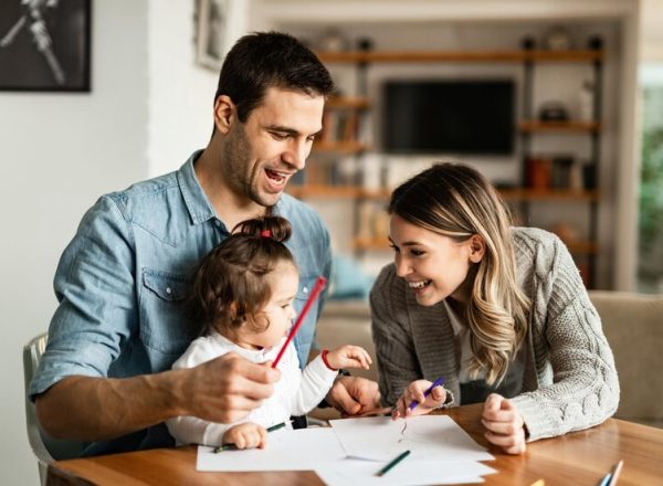 felices-padres-su-pequena-hija-divirtiendose-mientras-colorean-papel_637285-10221